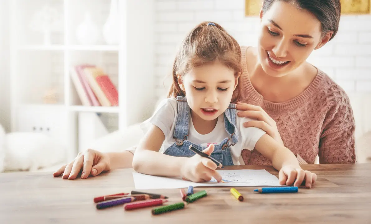 Smiling mother watching young daughter color